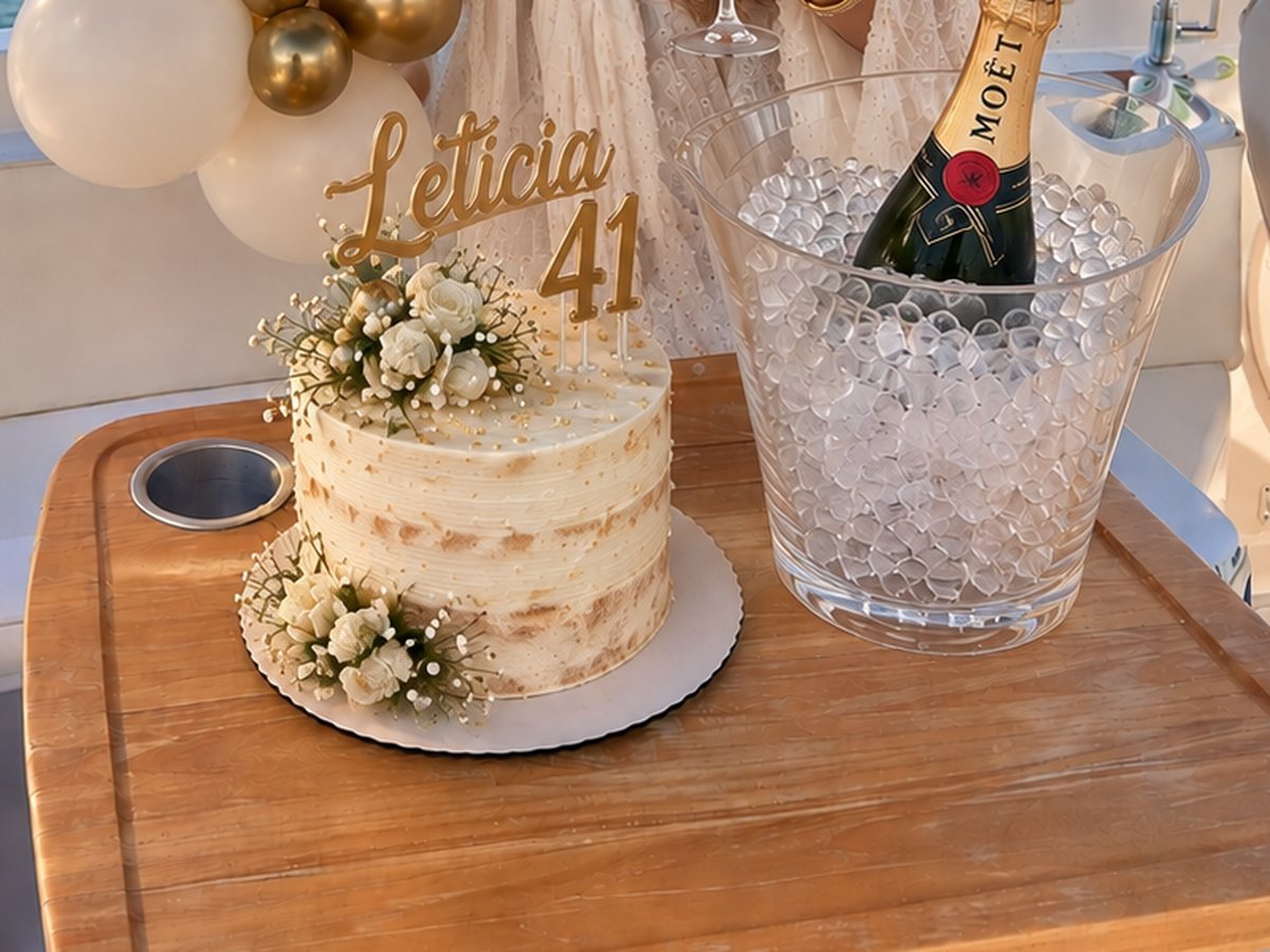 Bolo de aniversário decorado com flores e balde de gelo com espumante servidos a bordo